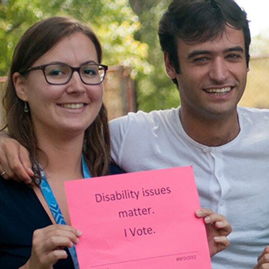 A man and a woman holding a pink sign that reads 